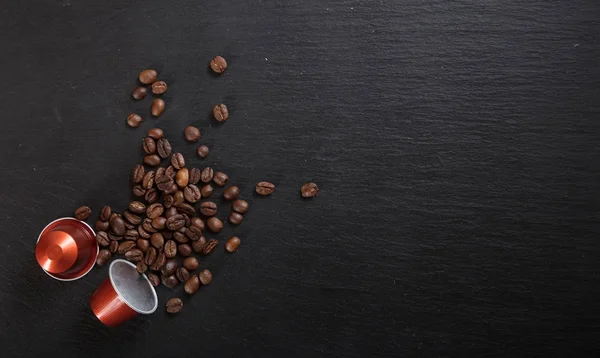 Кофейные стручки эспрессо и кофейные зерна на черном фоне, Вид сверху с копировальным пространством — стоковое фото