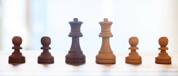 Pièces d'échecs sombre, couleur brun clair. Vue rapprochée des reines et des pions avec des détails. Fond flou . — Photo