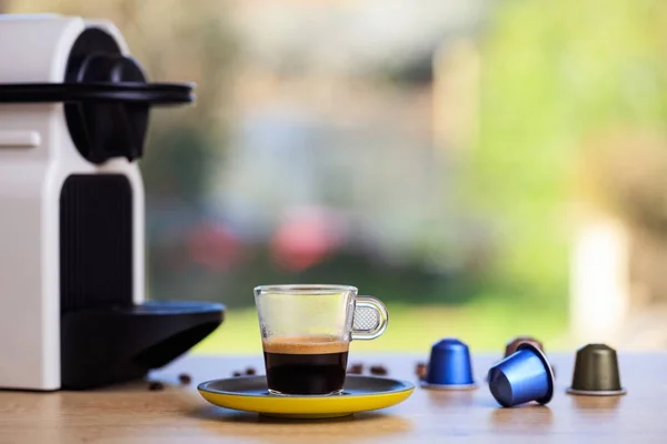 Tasse à café et machine à expresso et capsules sur fond flou, Vue rapprochée avec détails — Photo