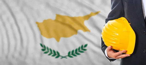 Инженер держит жёлтую каску на фоне флага Кипра. 3d иллюстрация — стоковое фото