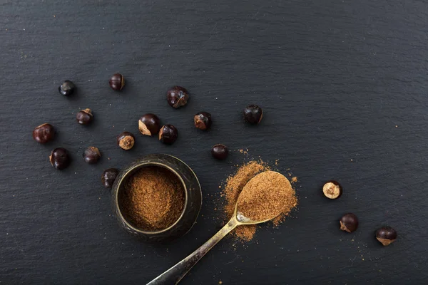 Tuercas de guaraná y polvo sobre fondo negro, vista superior, espacio para copiar — Foto de Stock