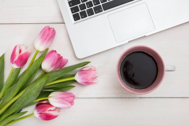 Kadınlar Günü. Pembe Laleler, dizüstü bilgisayar ve bir fincan kahve bir beyaz masa görünümü top