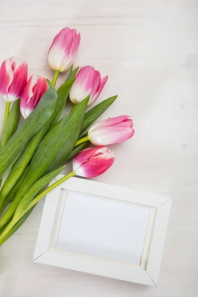 Dia das mulheres. tulipas cor-de-rosa e um quadro em branco branco no fundo branco, espaço de cópia, vista superior — Fotografia de Stock