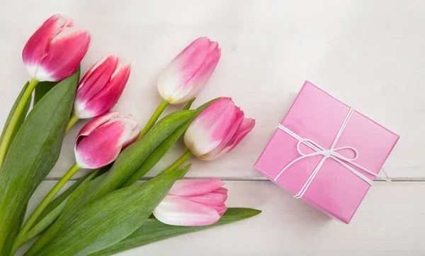 Día de las mujeres. Tulipanes rosados y un regalo sobre fondo blanco, vista superior — Foto de Stock