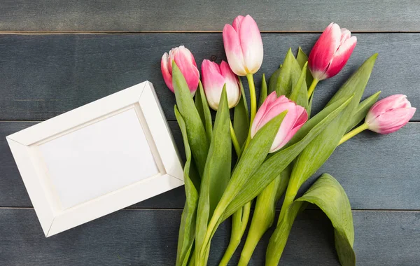 Día de la Madre. Tulipanes rosados y un marco blanco en blanco sobre fondo azul, espacio para copiar, vista superior — Foto de Stock