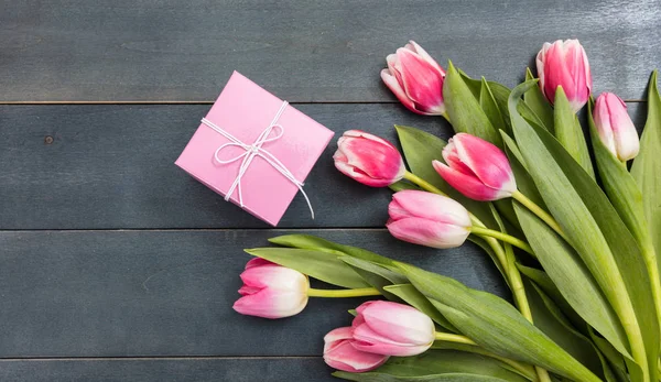 Día de las mujeres. Tulipanes rosados y un regalo sobre fondo azul, espacio para copiar, vista superior — Foto de Stock