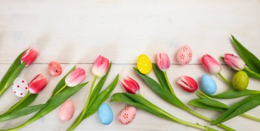 Paskalya kavramı. Pembe Laleler ve Paskalya yumurta beyaz ahşap zemin, kopya alanı, üstten görünüm, afiş