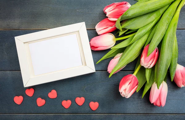 Dag van de vrouw. Roze tulpen en een leeg frame op blauwe achtergrond, bovenaanzicht — Stockfoto