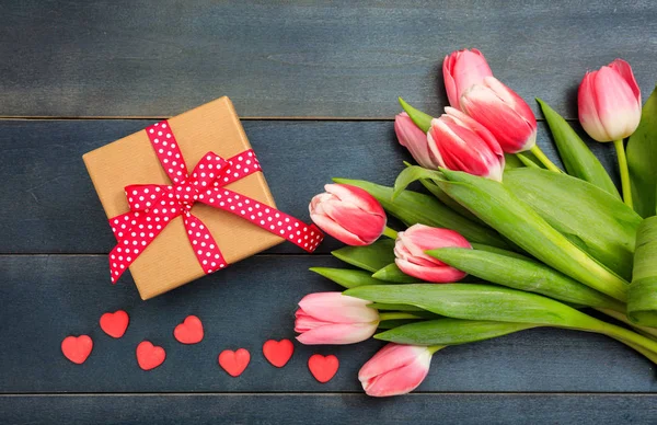 Dag van de vrouw. Roze tulpen en een cadeau op blauwe achtergrond, bovenaanzicht — Stockfoto