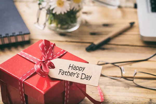 День отца. Красная подарочная коробка с ярлычком на день отца, на фоне размытого рабочего стола — стоковое фото