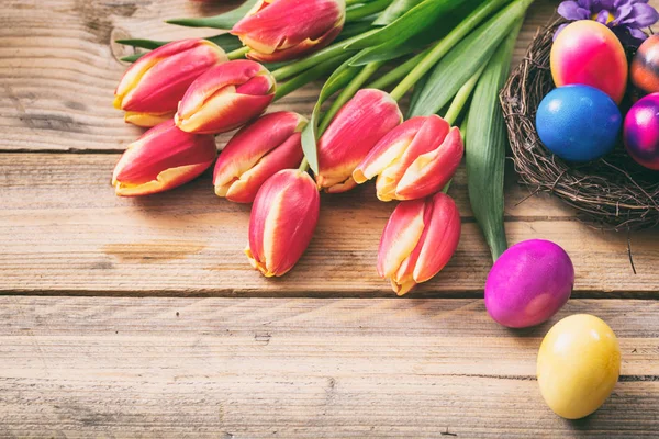 Ovos de Páscoa e tulipas frescas em fundo de madeira, espaço de cópia — Fotografia de Stock