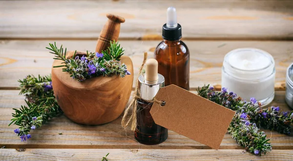 Aromaterapia al rosmarino. Olio essenziale e cosmetici, targhetta bianca, banner. Sfondo tavolo in legno — Foto Stock