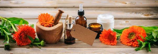 Aromaterapia di Calendula. Olio essenziale e cosmetici, targhetta bianca, banner. Sfondo tavolo in legno — Foto Stock