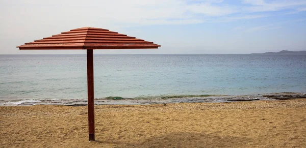Fa esernyő üres homokos strandon. Kék ég és a tenger nyugodt háttér. — Stock Fotó