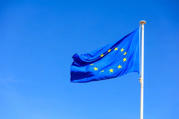 Прапор ЄС. Прапор Європейського Союзу на полюс, розмахуючи на фоні синього неба — стокове фото