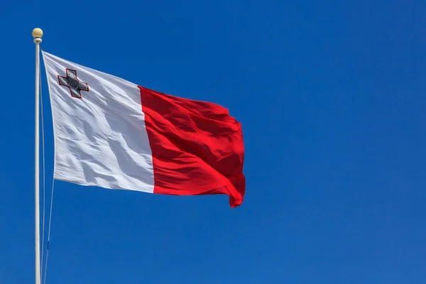 Прапор Мальти. Прапор Мальти на полюс, розмахуючи на фоні синього неба — стокове фото