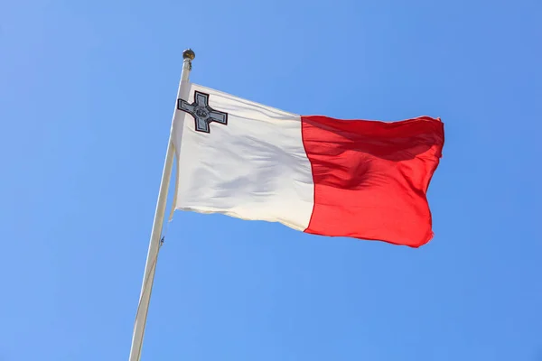 Прапор Мальти. Прапор Мальти на полюс, розмахуючи на фоні синього неба — стокове фото