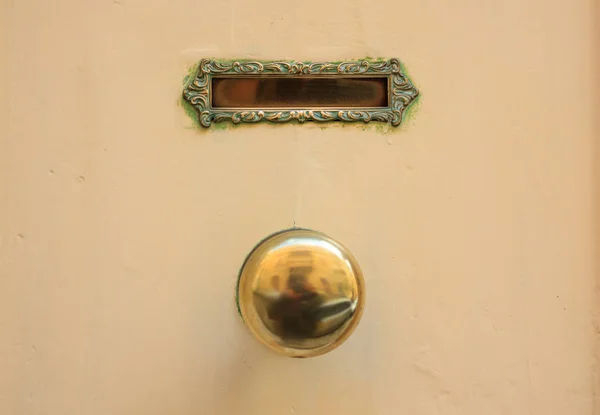 Oude koperen mail brievenbus en knop op een gele geschilderde voordeur — Stockfoto