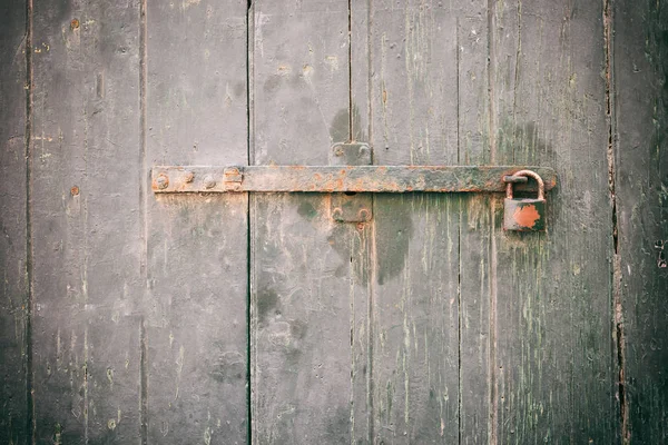 Locked door. Closed old rusty padlock on a weathered wooden door