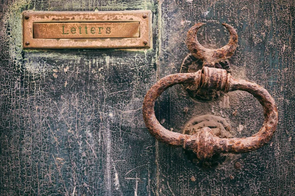 Eski paslı posta mektup kutusu ve yıpranmış bir ön kapı, metin harfler üzerinde paslı tokmağı — Stok fotoğraf