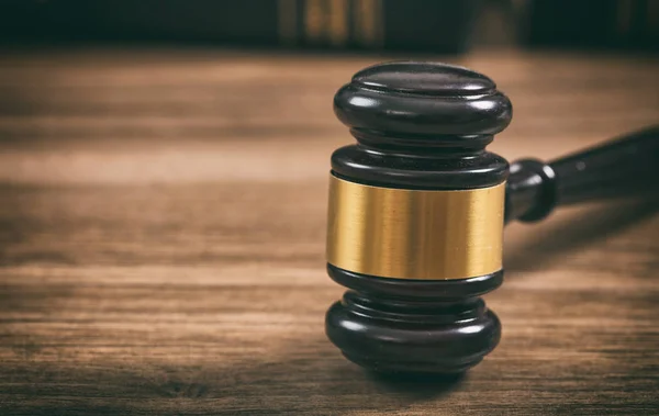 Law or auction gavel on a wooden office desk. Closeup front view, copy space