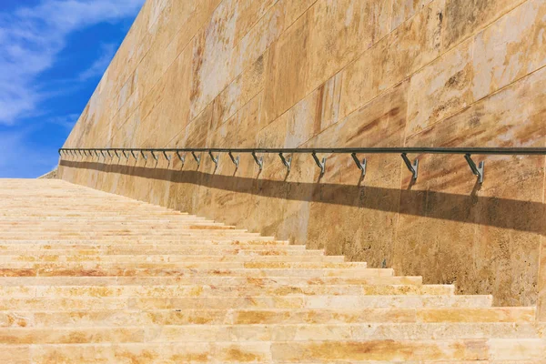 Σκάλες από την πέτρα και τοίχων με μέταλλο ραγών για το ιστορικό κέντρο της Βαλέτας, Μάλτα. Φόντο μπλε του ουρανού — Φωτογραφία Αρχείου
