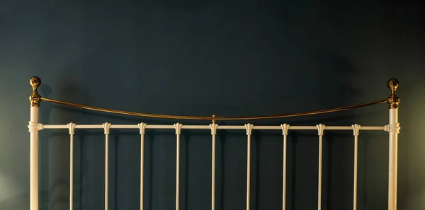 Metal bed headboard on black wall background, copy space