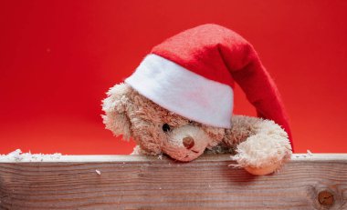 Noel Baba şapkalı oyuncak ayı, kırmızı arkaplan