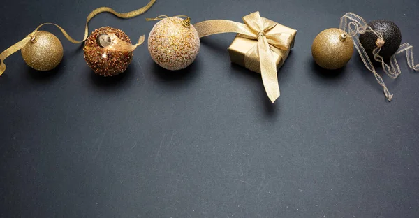 Navidad presente y bauble color dorado brillante sobre fondo gris negro — Foto de Stock