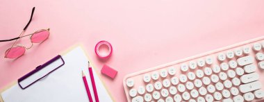 Pembe arka plana karşı bilgisayar klavyesi ve ofis malzemeleri