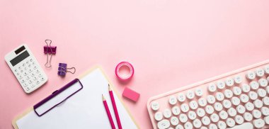 Pembe arka plana karşı bilgisayar klavyesi ve ofis malzemeleri