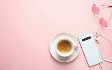 Pembe arka planda akıllı telefon ve kahve fincanı
