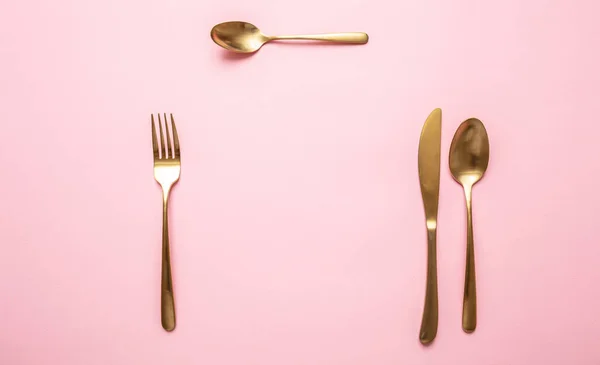 Arany evőeszközök szemben rózsaszín háttér, formális hely beállítása — Stock Fotó