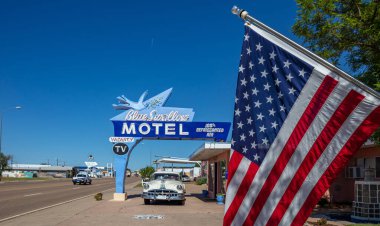 Mavi Kırlangıç Moteli 'nin bir bölümünü Amerikan bayrağı kaplıyor ve girişe de bir Pontiac arabası park edilmiş. Tucumcari, New Mexico, ABD.