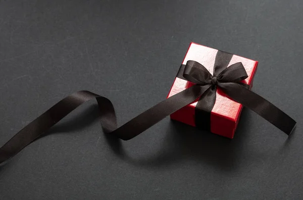 Gift box with black ribbon against black background, Black Friday concept.