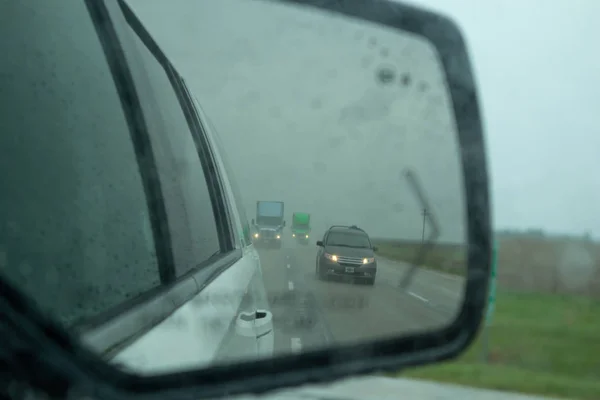 Vehículos en una carretera se reflejan en un espejo de coche durante una lluvia en el país de EE.UU. —  Fotos de Stock