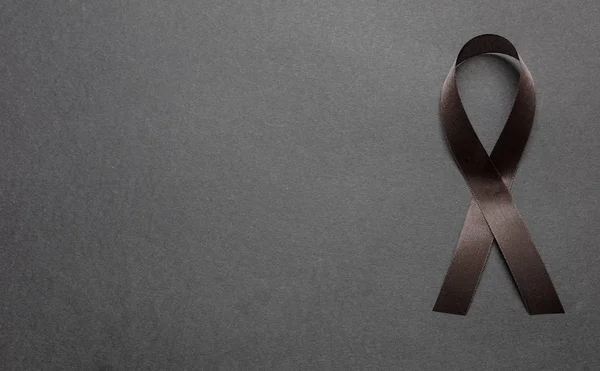 Black awareness ribbon on black color background. Melanoma and sorrow concept — Stock Photo, Image