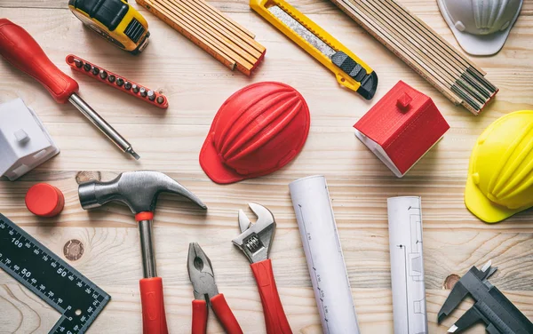 Araçlar, kasketler ve proje planları ahşap masa, üst görünüm.