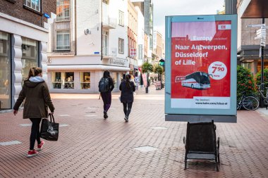 Reklam paneli ve şehir merkezindeki bir iş caddesinde yürüyen insanlar. Eindhoven, Hollanda