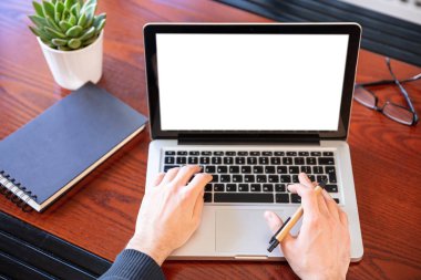 Ahşap bir masanın üstünde beyaz beyaz ekranlı bir laptop.