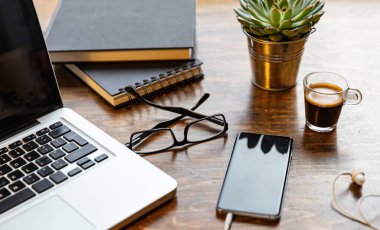 İş yeri. Ahşap ofis masasında bilgisayar ve cep telefonu.