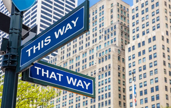 This way, that way crossroads street sign. Highrise buildings background,