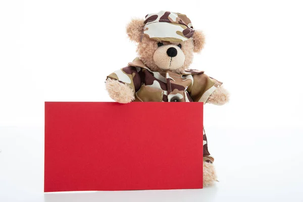 Schattige teddybeer in soldaat uniform en een blanco rode kleur kaart geïsoleerd tegen witte achtergrond — Stockfoto