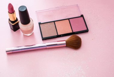 Allık tozu ve fırça, ruj ve oje pembe arka planda.