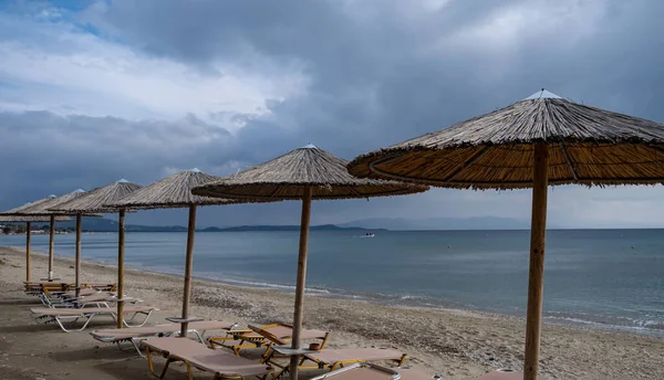 Szalmaernyők és strandszékek homokos strandon. — Stock Fotó