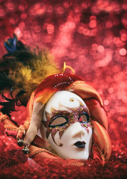 Carnival mask female theatrical face against red bokeh background. Festive party celebration