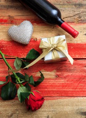 Sevgililer Günü. Kırmızı şarap şişesi, güller ve tahtadan bir hediye.