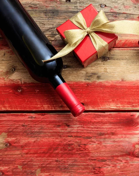 Saint Valentin. Bouteille de vin rouge et cadeau sur bois — Photo