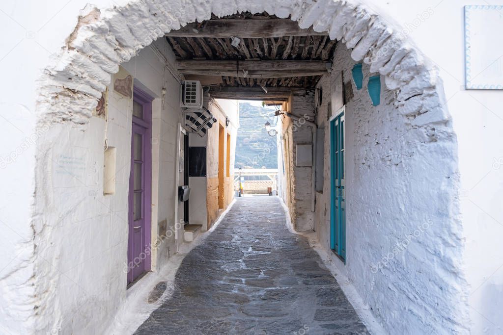 Traditional greek whitewashed buildings, cobblestone streets and stone structure arch. Ioulida village,Tzia, Kea island, Greece.