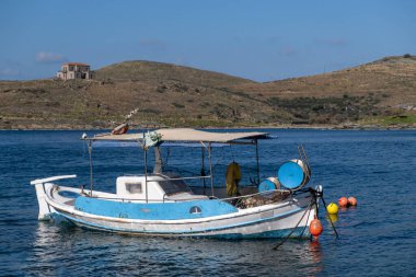 Tzia, Kea, Yunanistan. Mavi ve beyaz geleneksel balıkçı teknesi Vourkari Koyu 'nda durgun denizin ortasında demirledi..